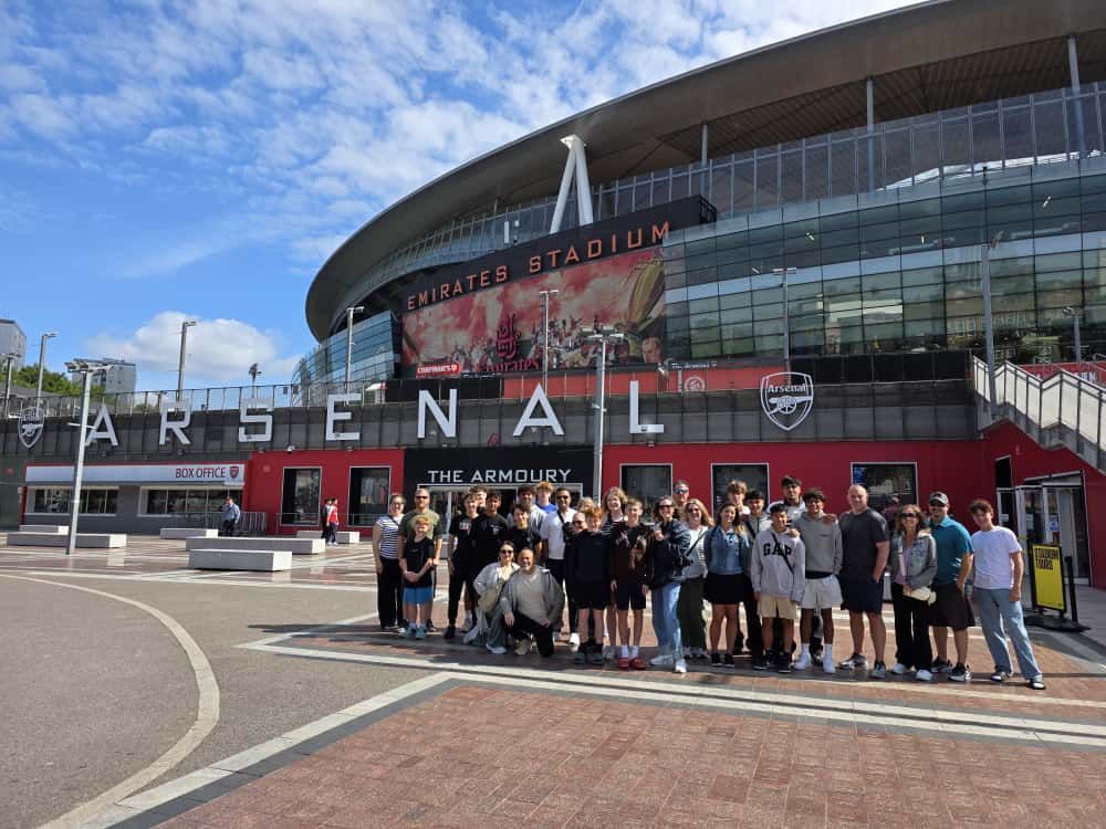 Group of people posing in front of Emirates Stadium, home of Arsenal Football Club.