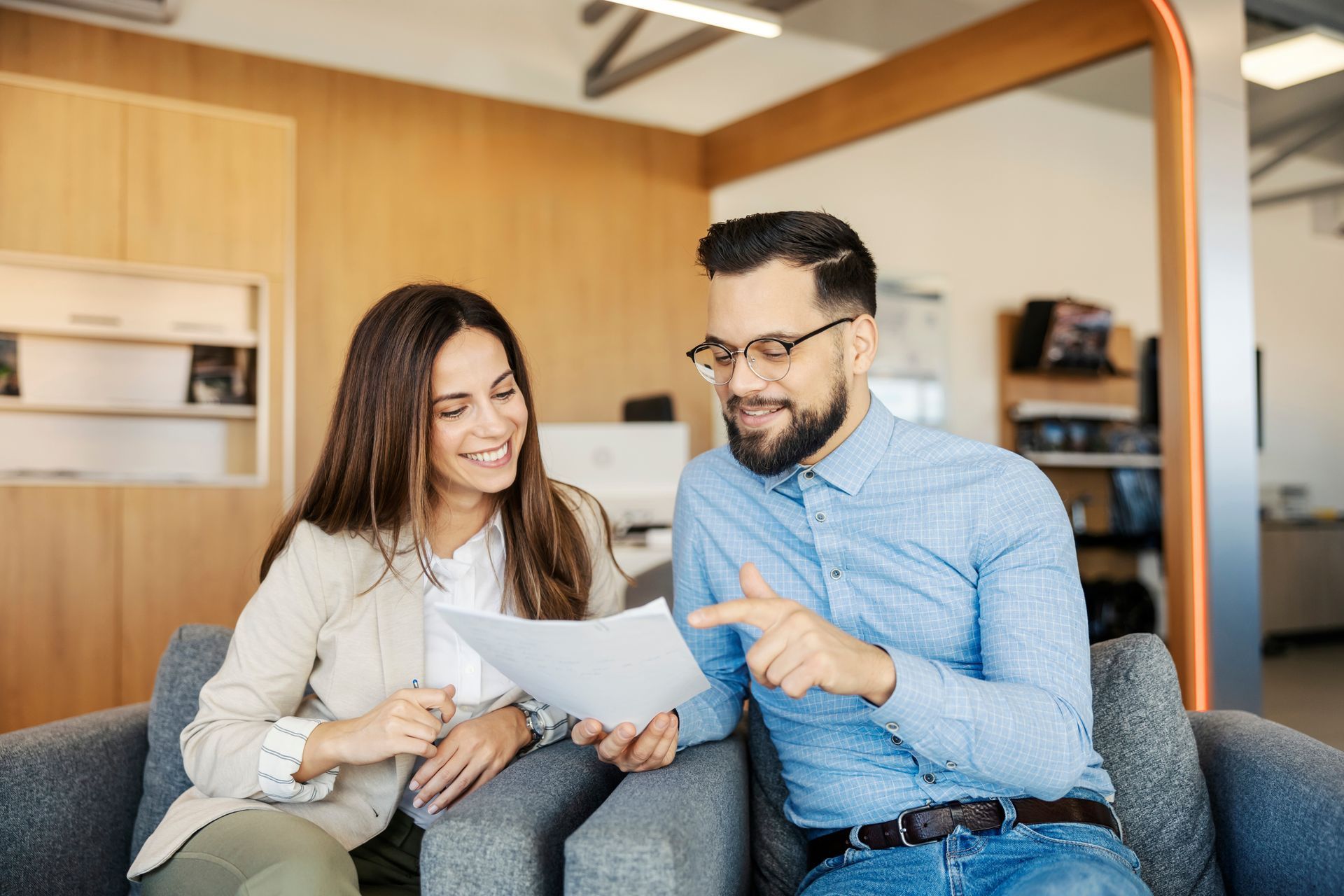 Woman and man smiling, reviewing documents in an office setting. Woman and man smiling, reviewing documents in an office setting.