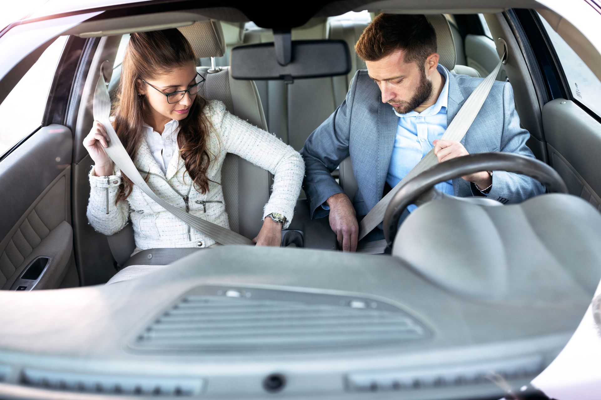 Woman and man inside a car, buckling seatbelts. Woman and man inside a car, buckling seatbelts.