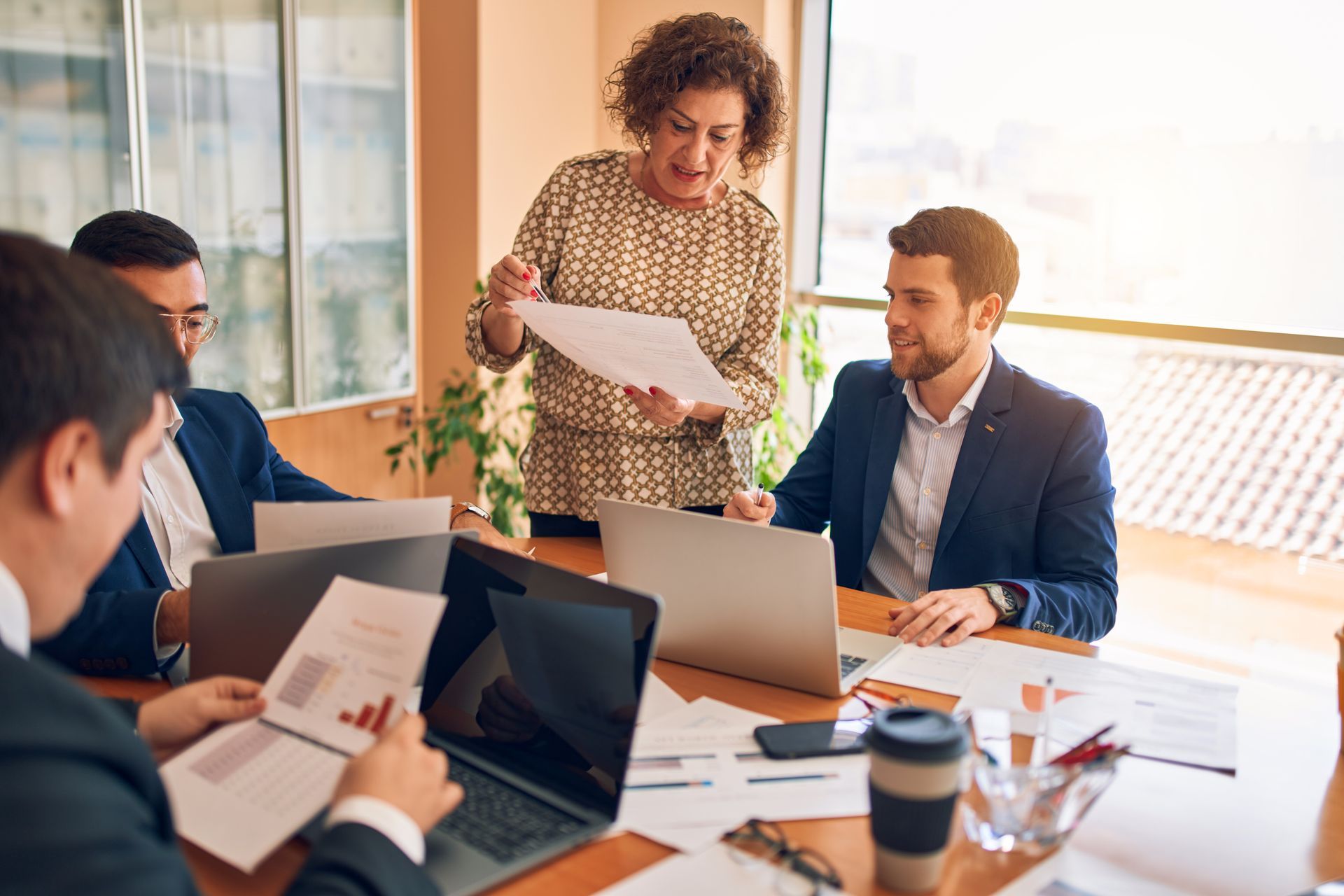 Business meeting: Woman presenting documents to colleagues around a table.