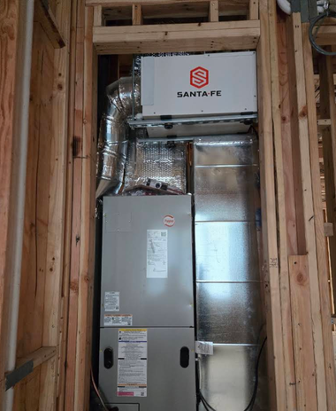 HVAC furnace and ductwork installed in a wooden-framed wall cavity