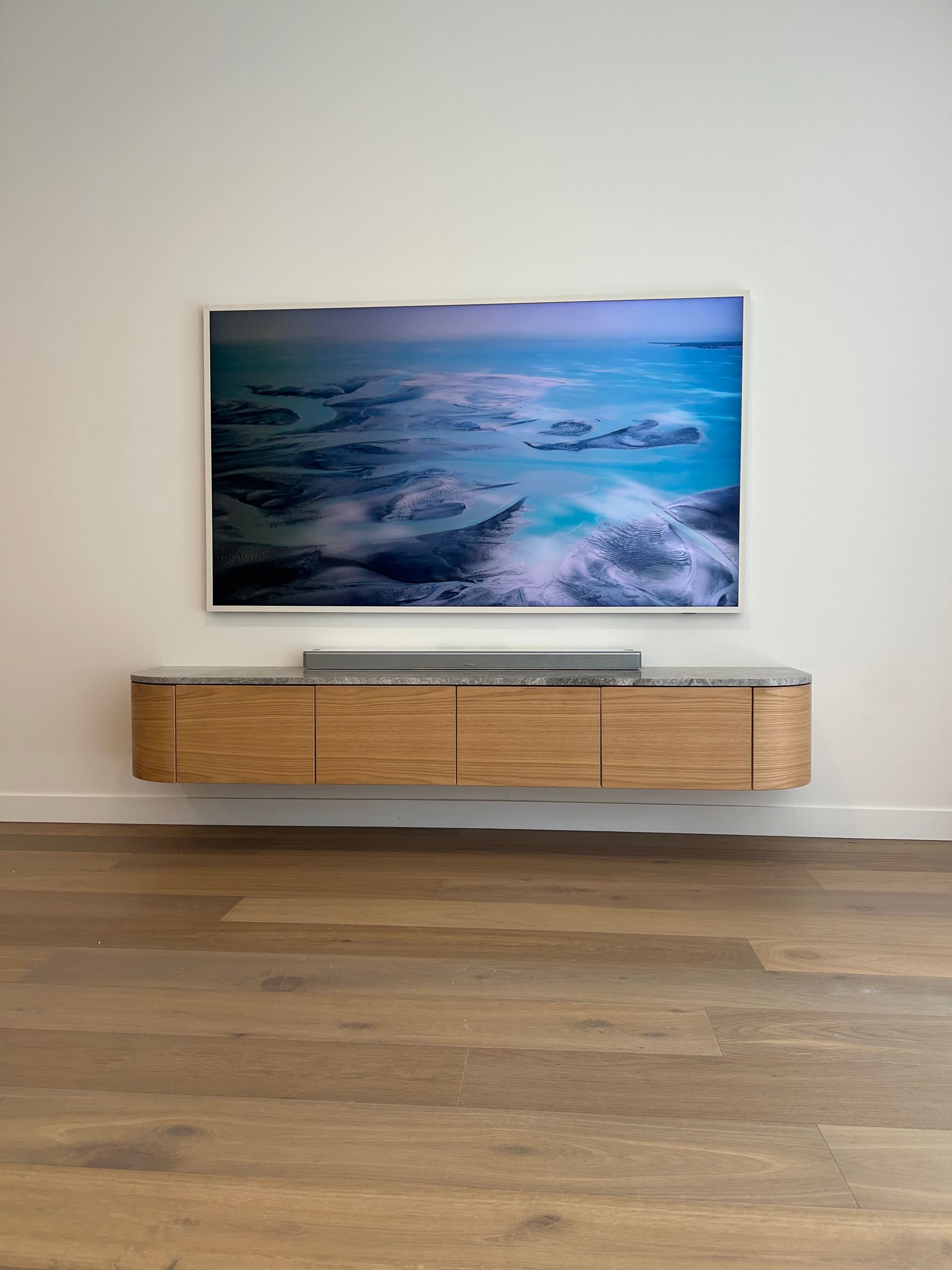 Two men are installing a flat screen tv in a living room.