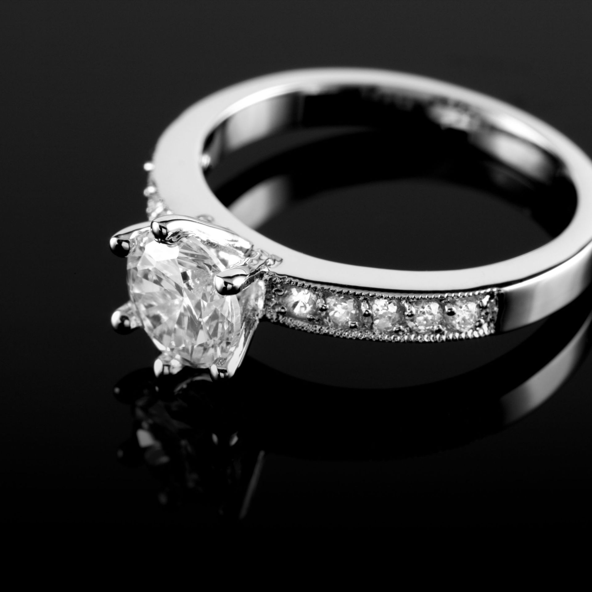 White gold diamond engagement ring with side stones on black background