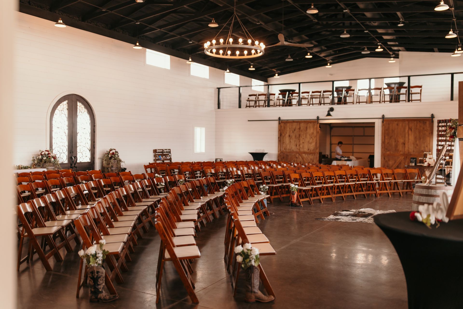 Curved rows of wooden chairs in a bright event hall with arched windows and a balcony