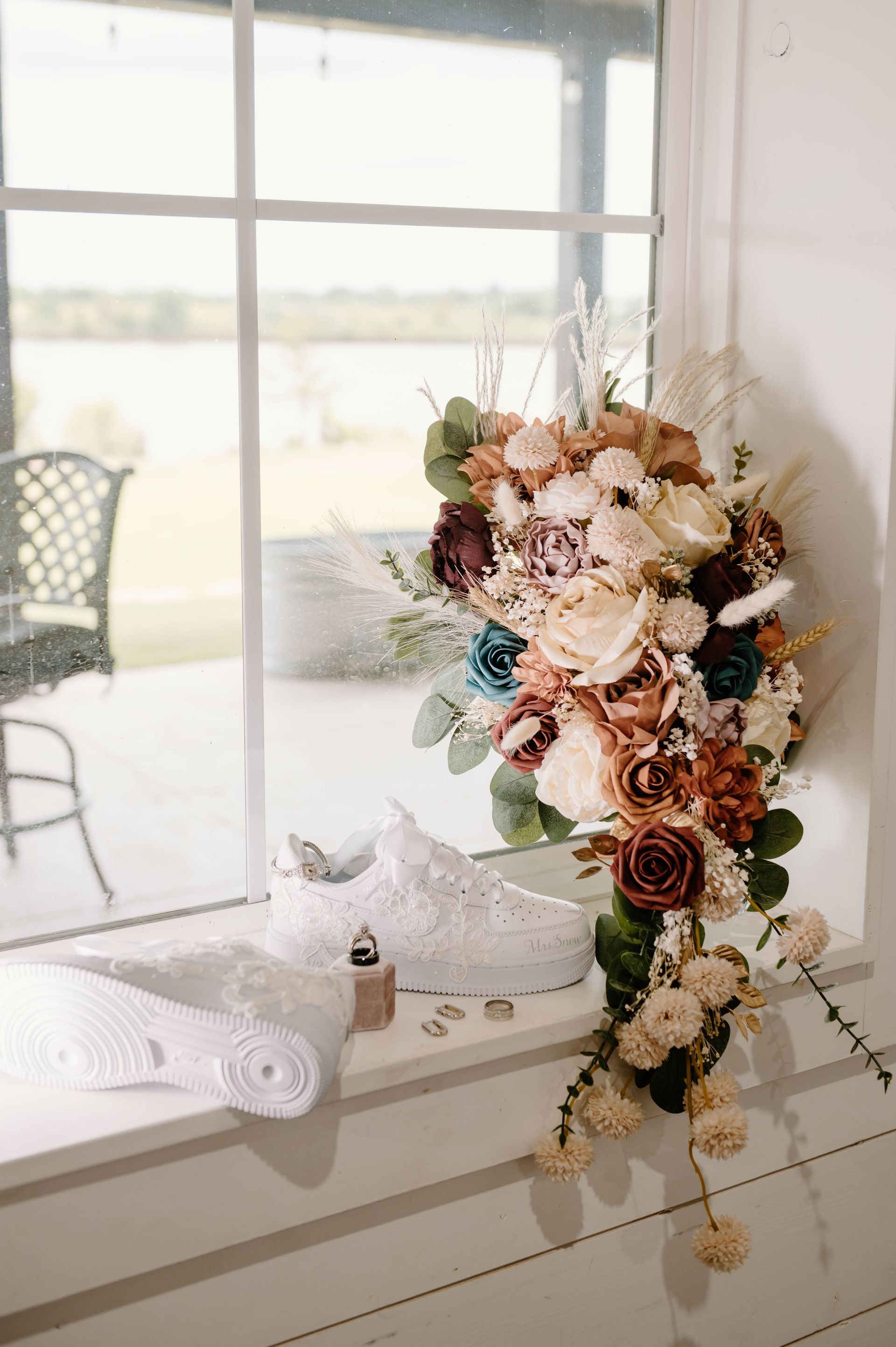 neutral toned wedding floral arrangement next to bride's sneakers