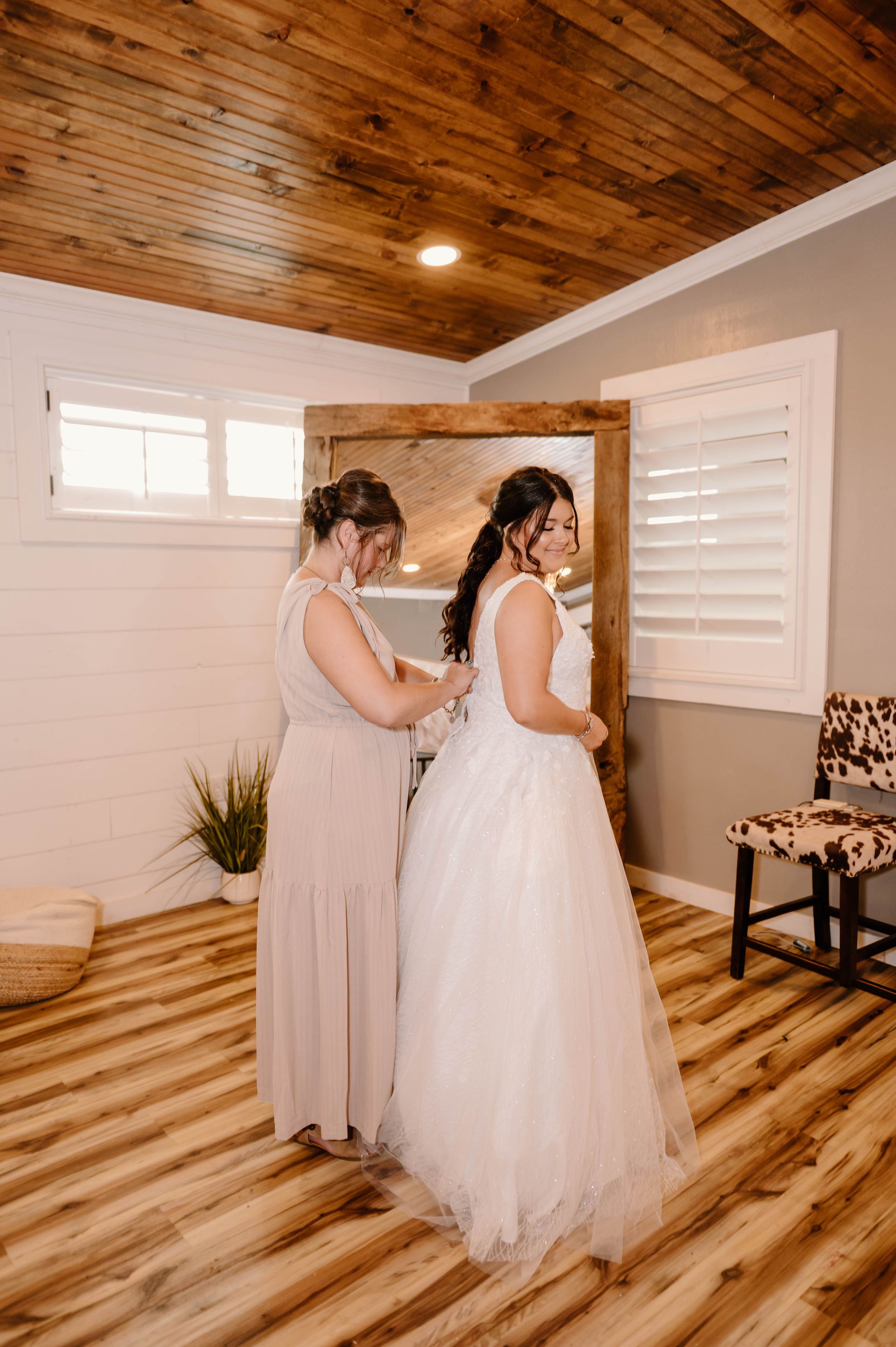 bridesmaid buttoning bride's gown