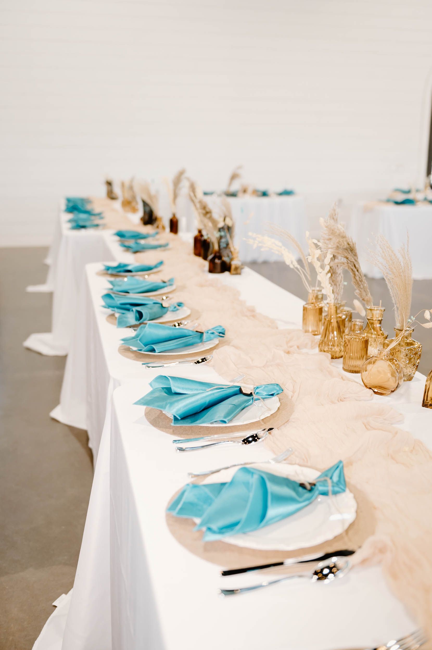 wedding reception table with blue napkins and pampas grass decor