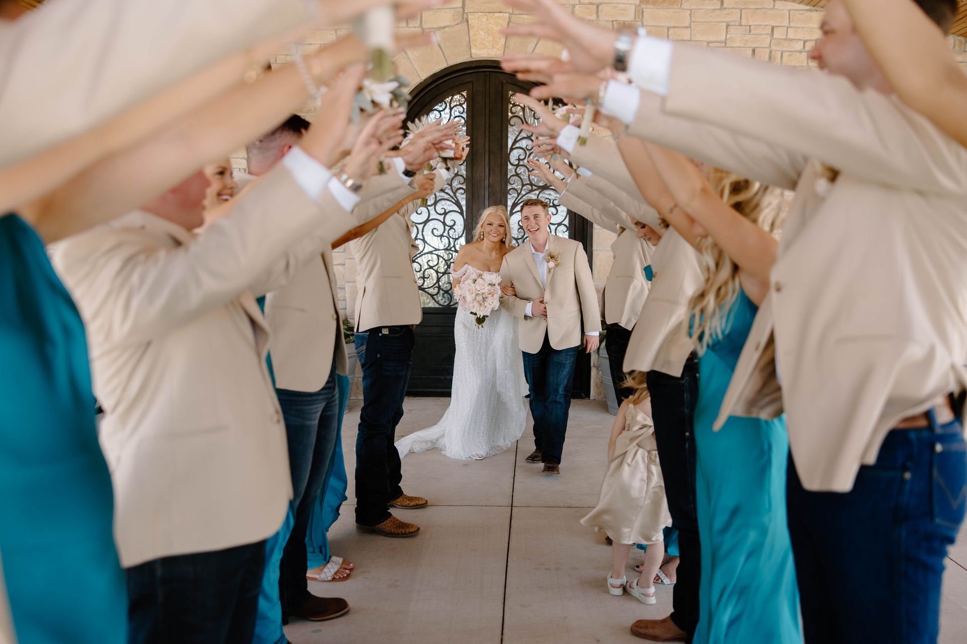 bride and groom walking through wedding party's raised arms