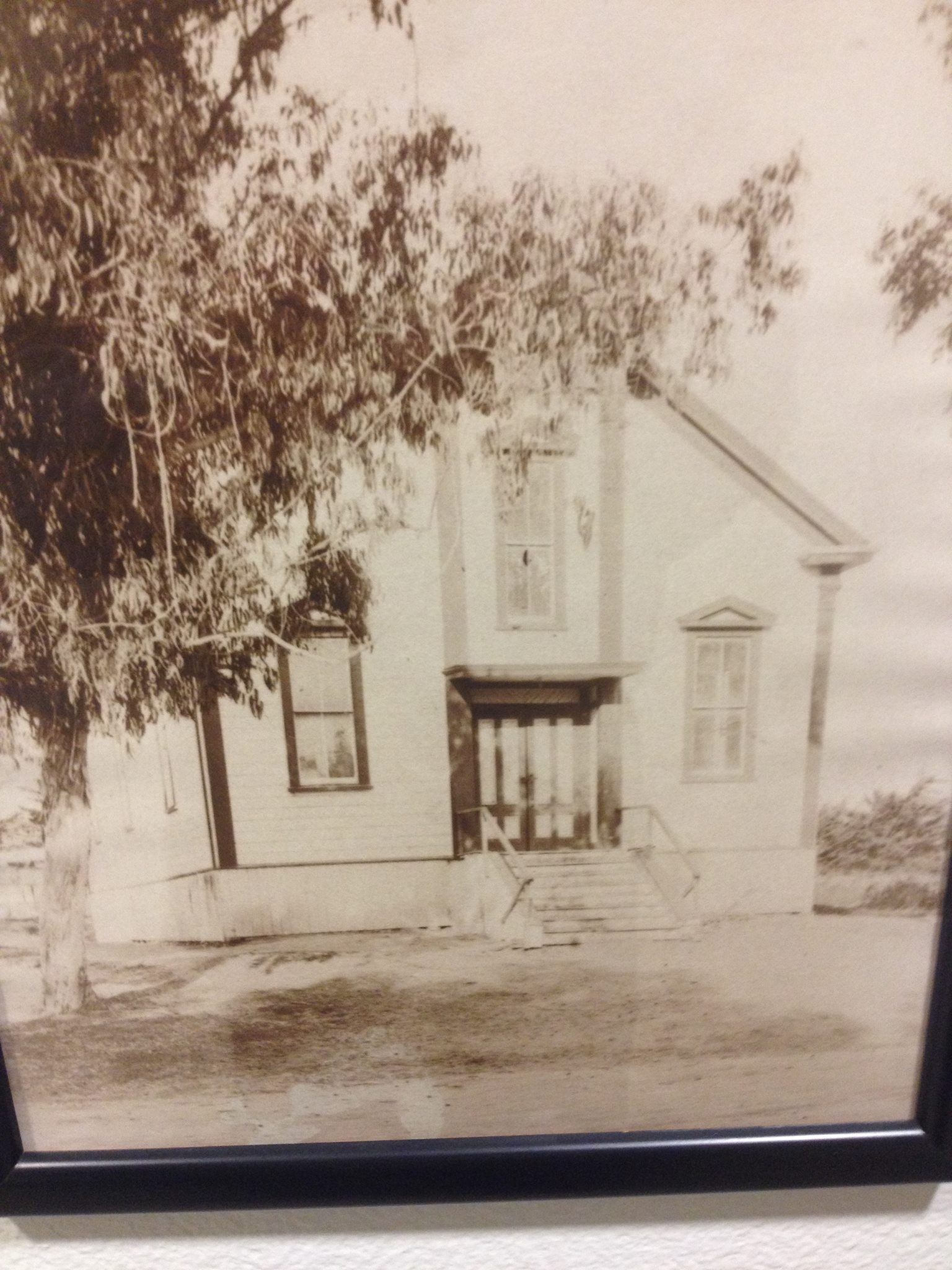 A black and white photo of a house with trees in the background