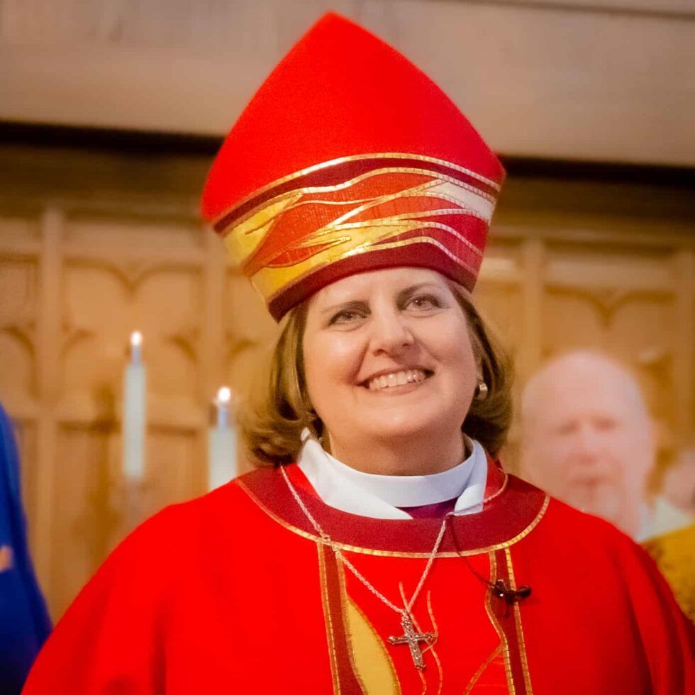 A woman wearing a red robe and a red hat is smiling
