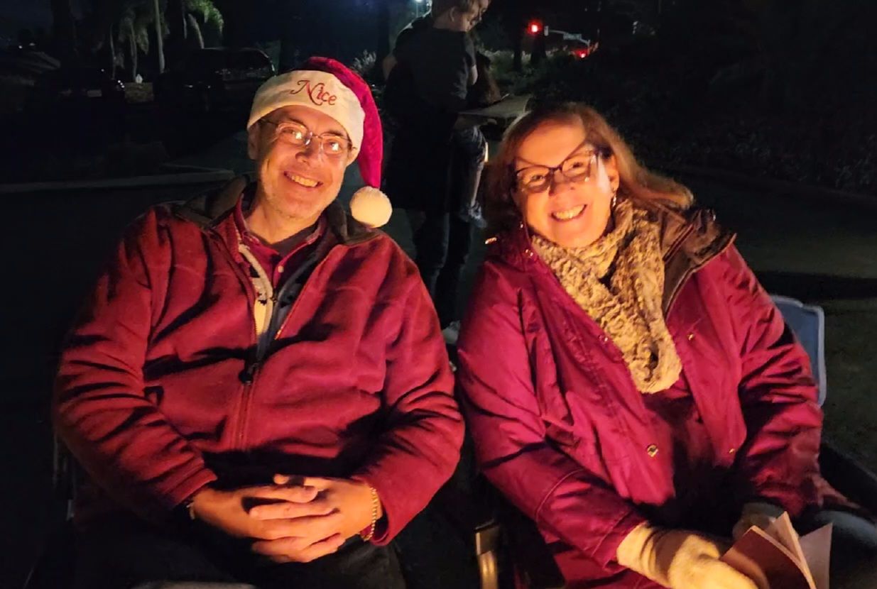 A man and a woman are sitting next to each other wearing santa hats