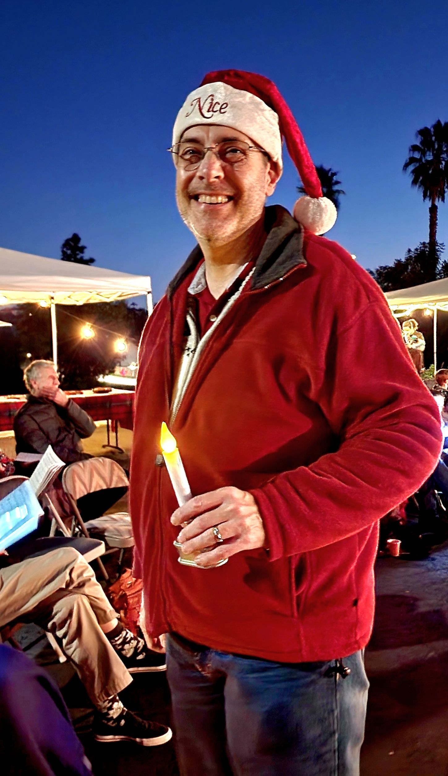 A man wearing a santa hat is holding a candle.