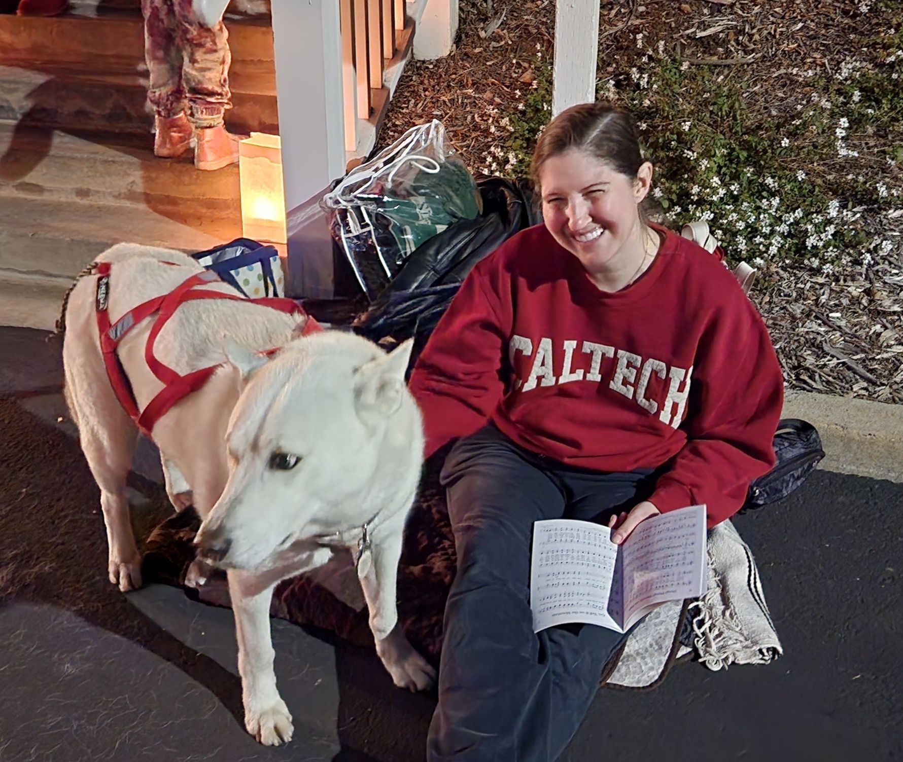 A woman wearing a caltech sweatshirt sits next to a dog