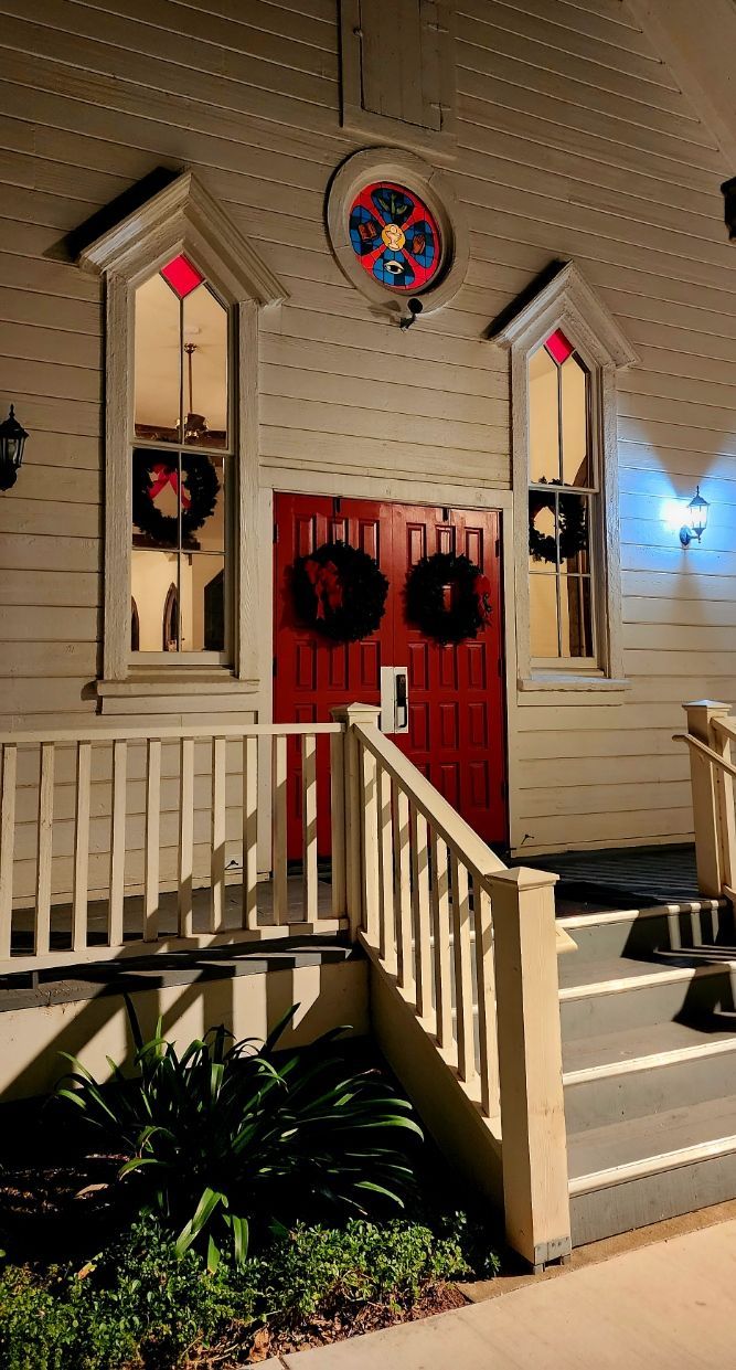 A white building with a red door and a stained glass window.