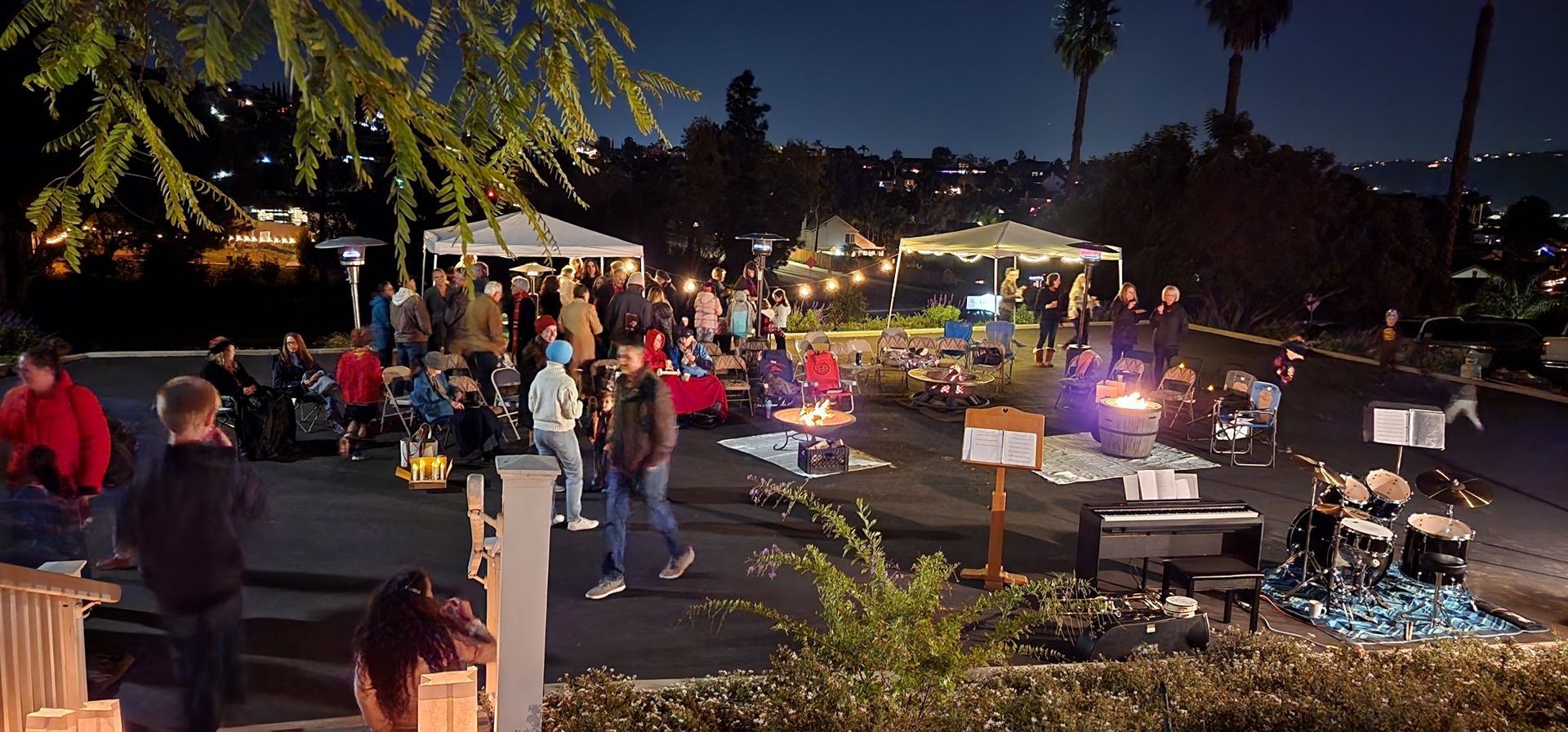 A group of people are gathered in a parking lot at night.