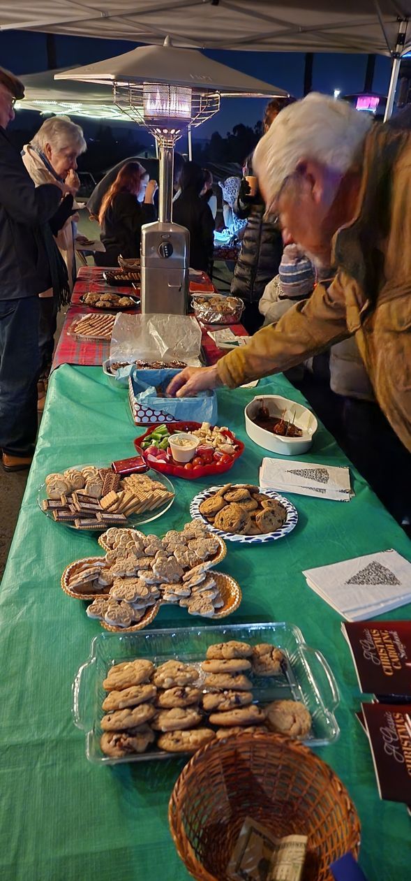 A man is standing at a table with plates of food on it.