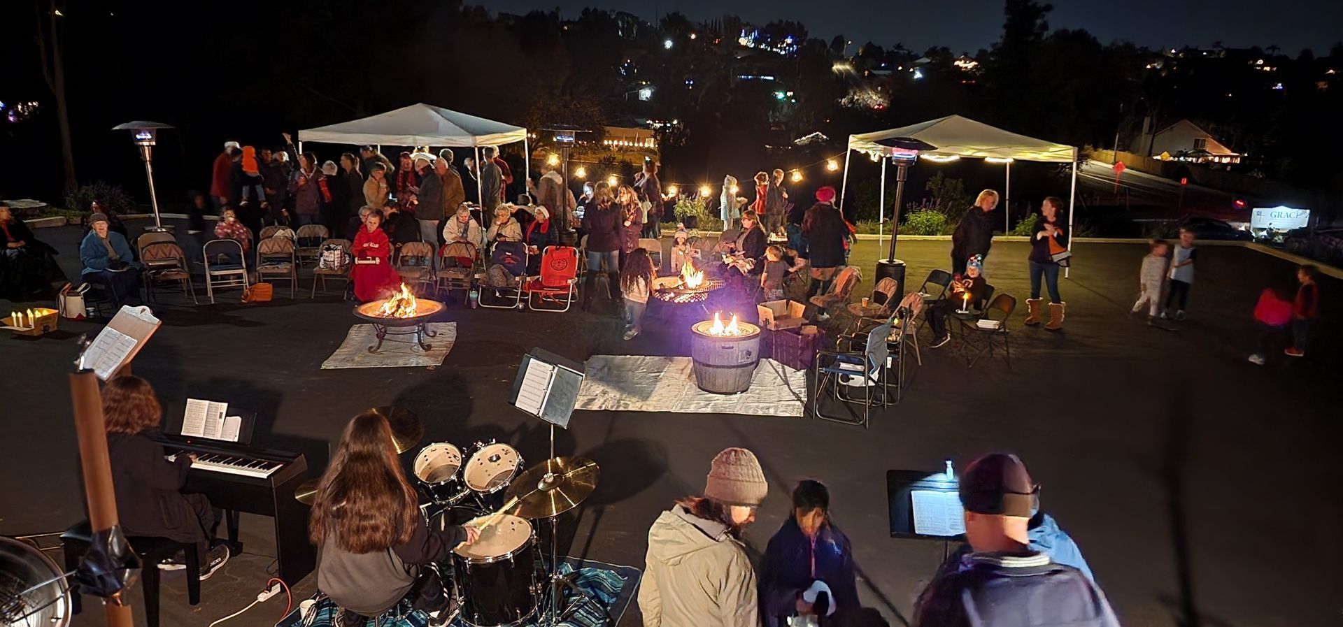 A group of people are sitting around a fire pit at night.