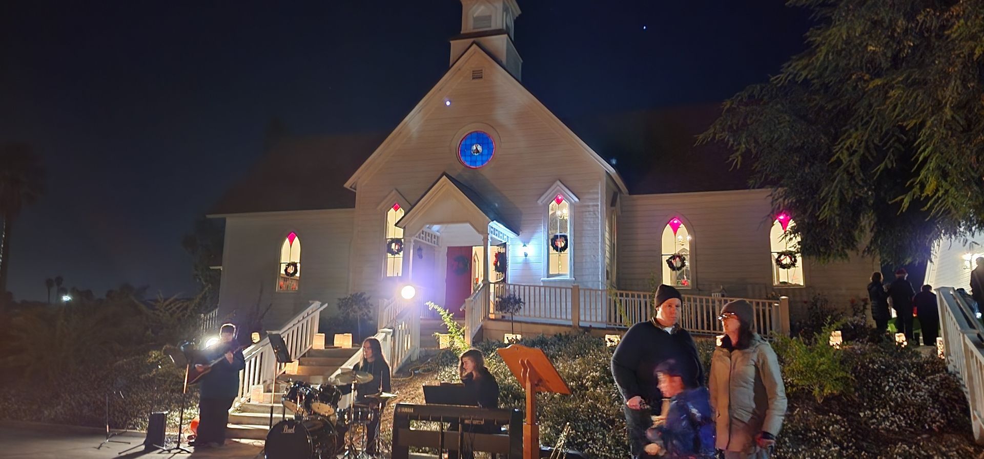 A group of people are standing in front of a church at night.