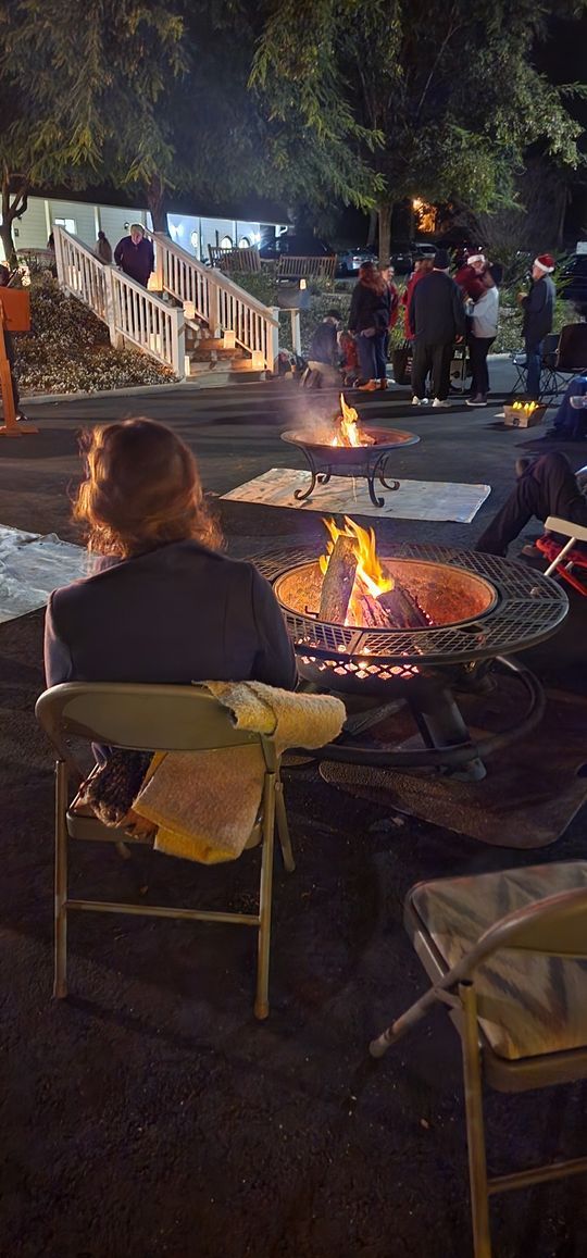 A group of people are sitting around a fire pit at night.