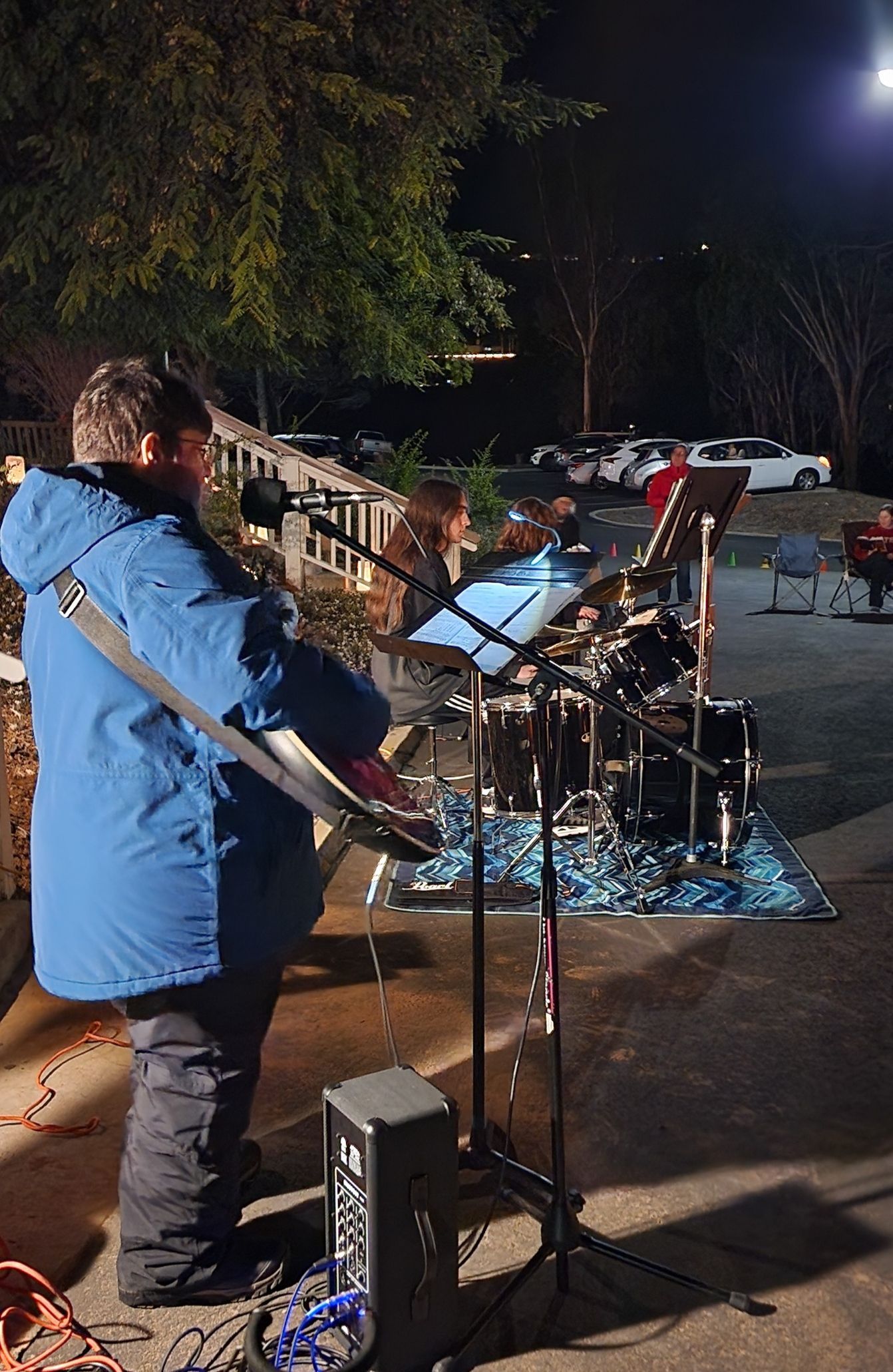 A man in a blue jacket is playing a guitar on a stage at night.