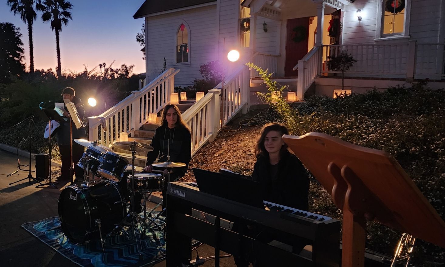 A group of people are playing instruments in front of a house.