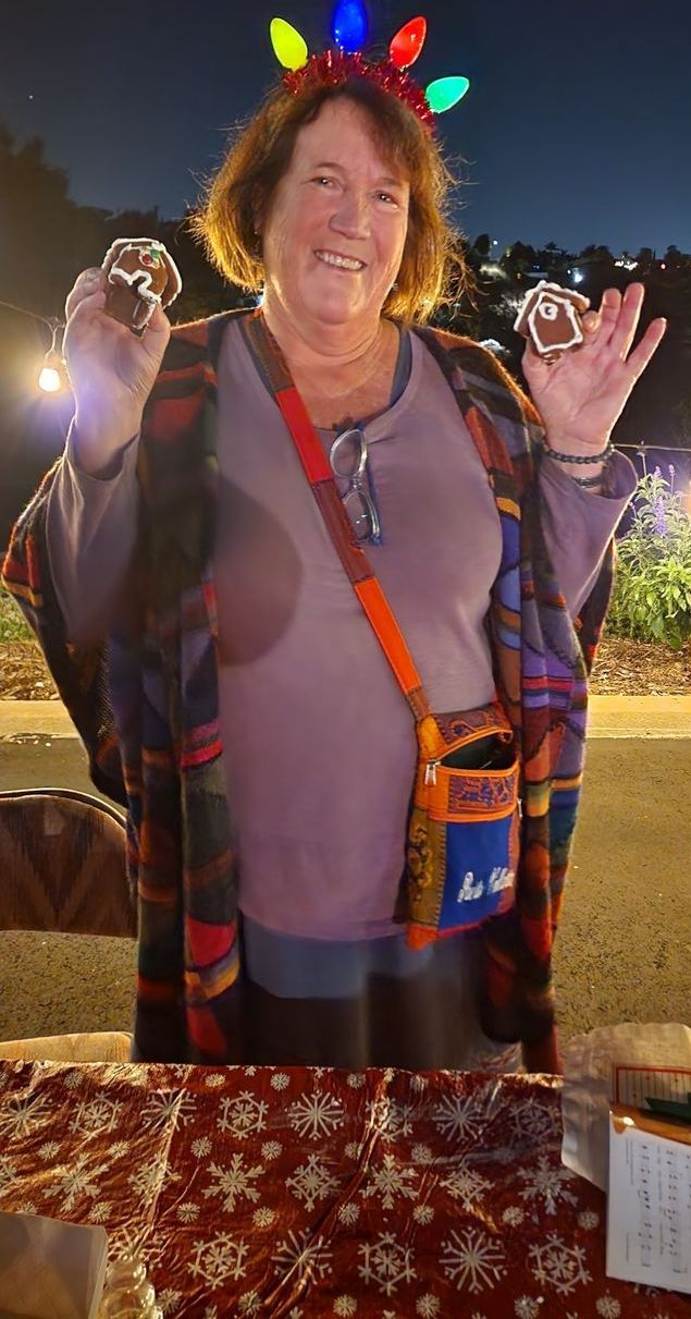 A woman wearing a christmas headband is holding two donuts in her hands.