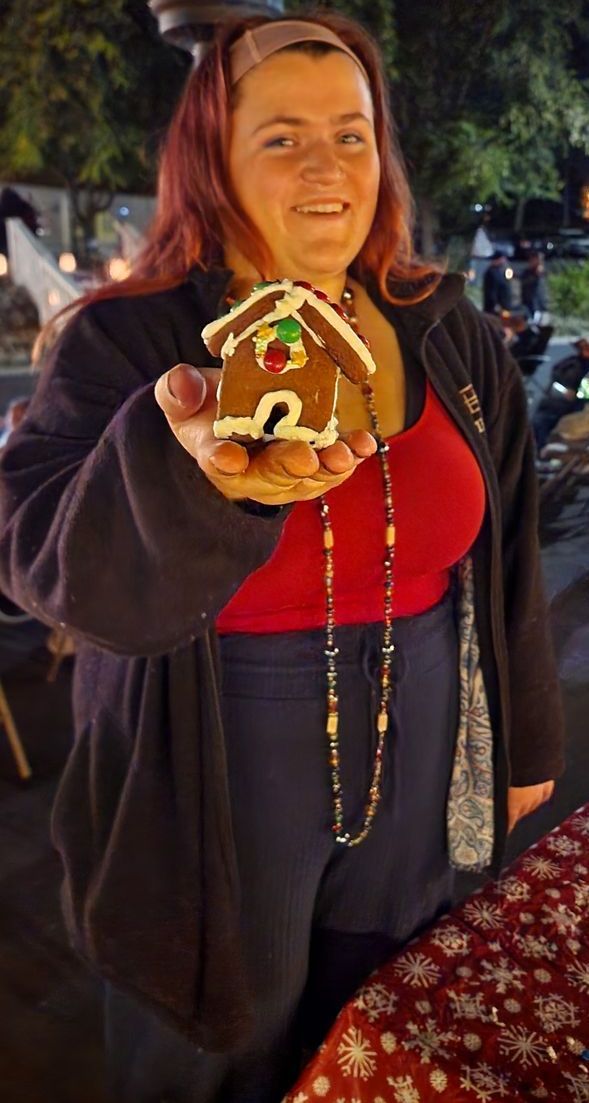 A woman is holding a gingerbread house with the number 2 on it