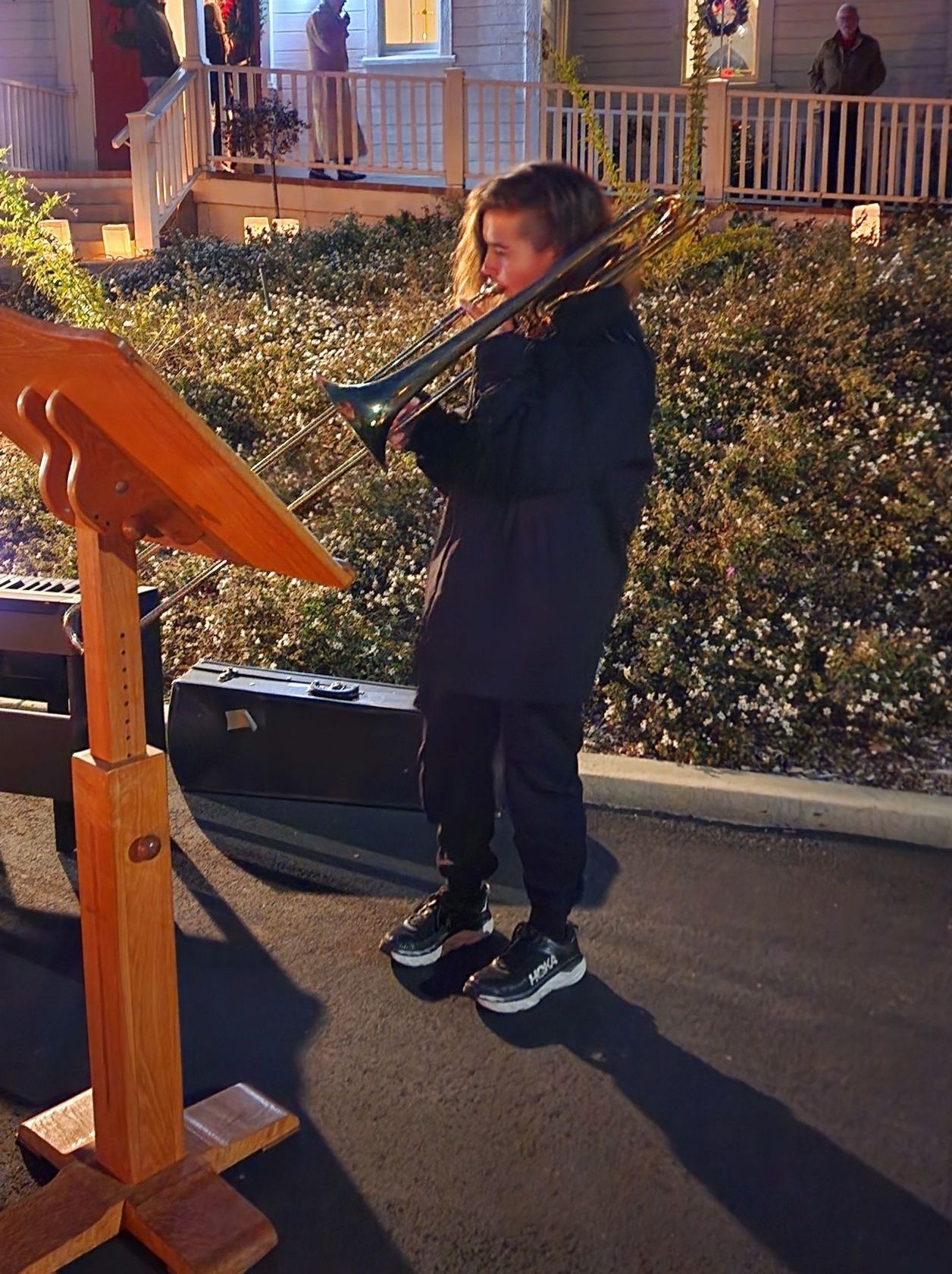 A young girl is playing a trombone in front of a house