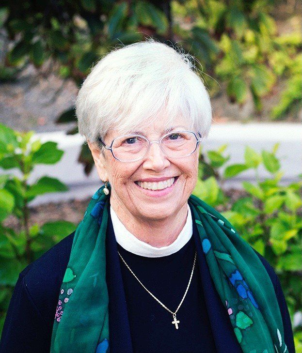 A woman wearing glasses and a green scarf is smiling for the camera.