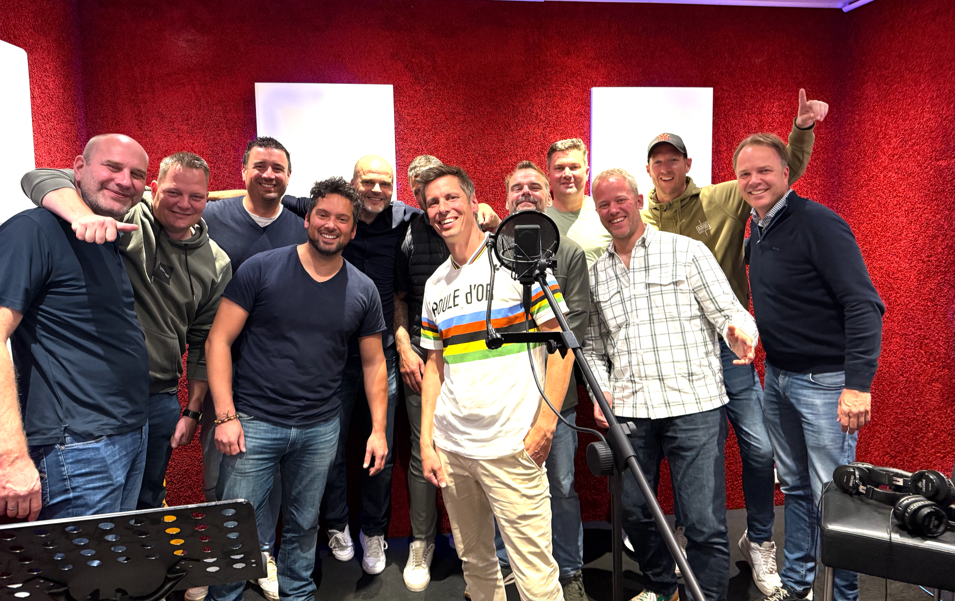 Een groep mannen poseert voor een foto voor een microfoon.