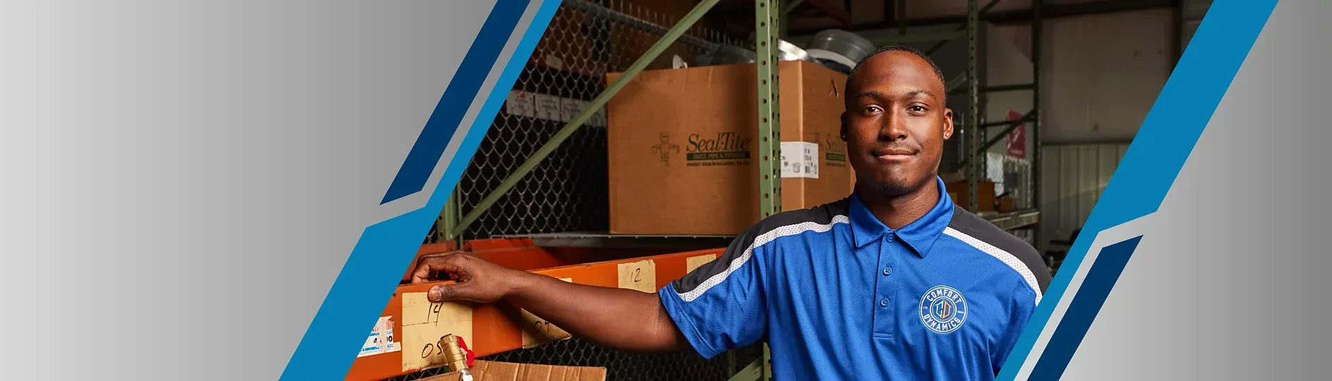 Warehouse worker in blue shirt smiling, near shelves of boxes.