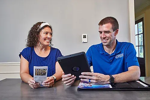 Woman and man looking at tablet and brochure, smiling, indoors.