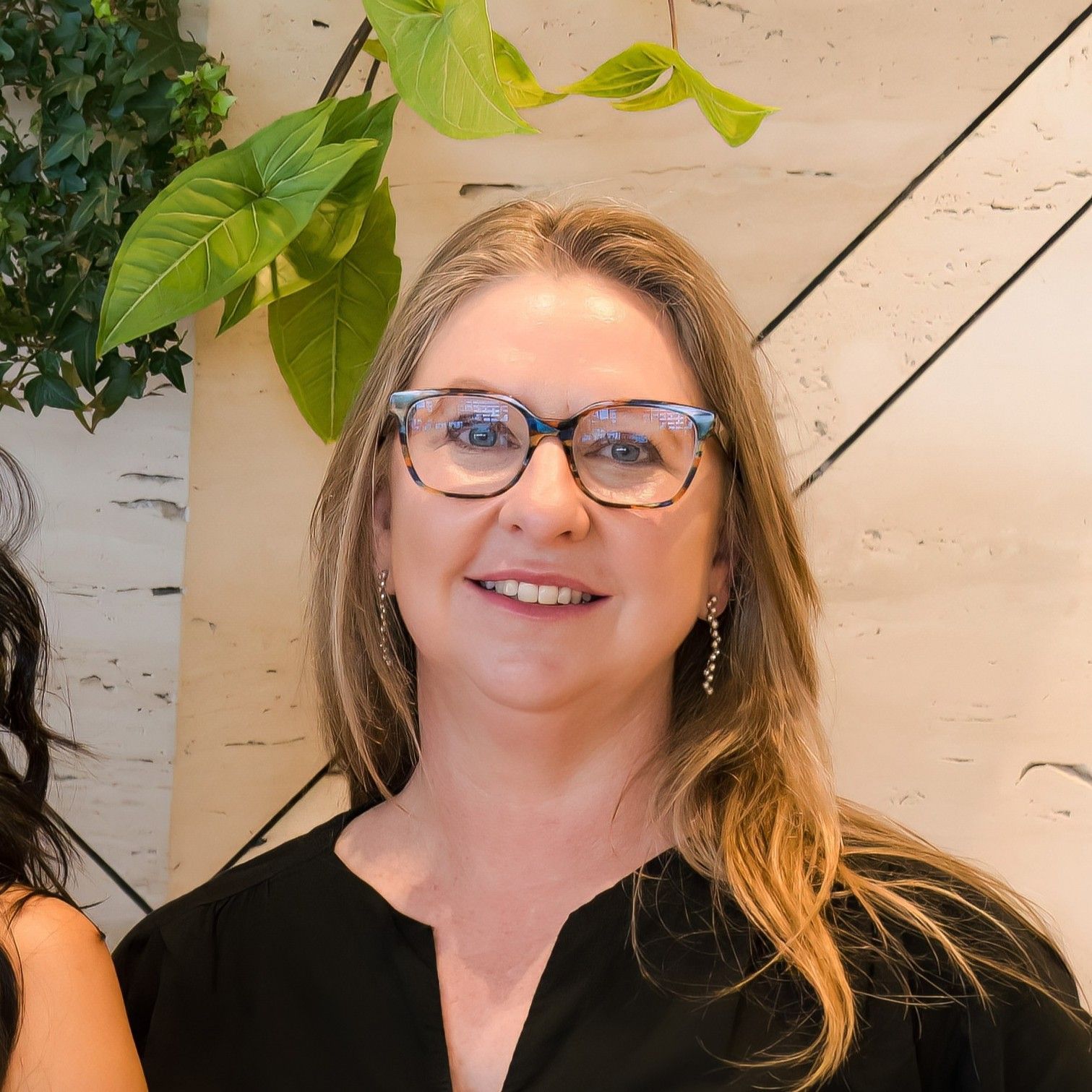 Aurora Bariatrics team member smiling in front of a feature wall with greenery