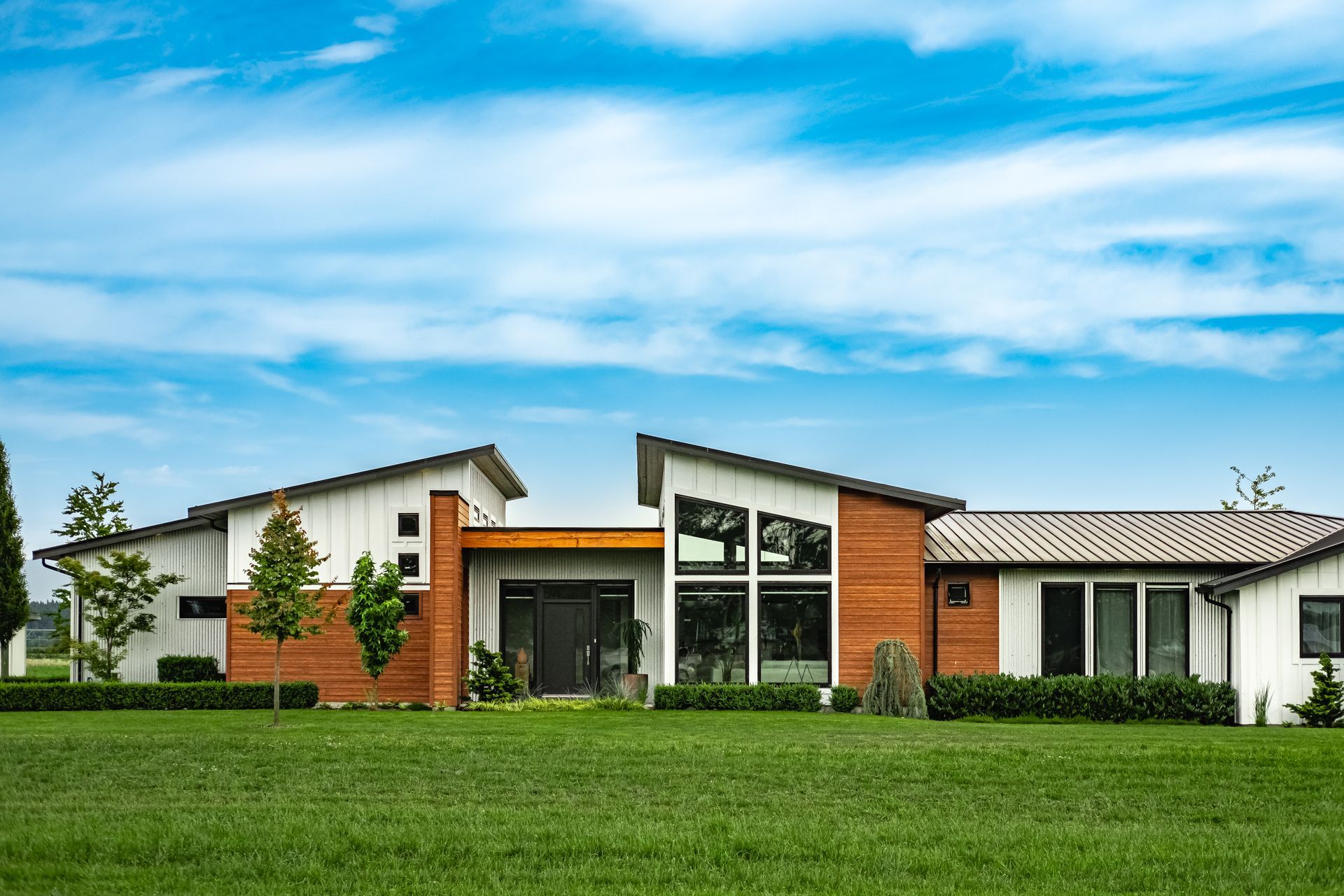 A luxurious custom-built home on a sunny day with a landscaped yard.