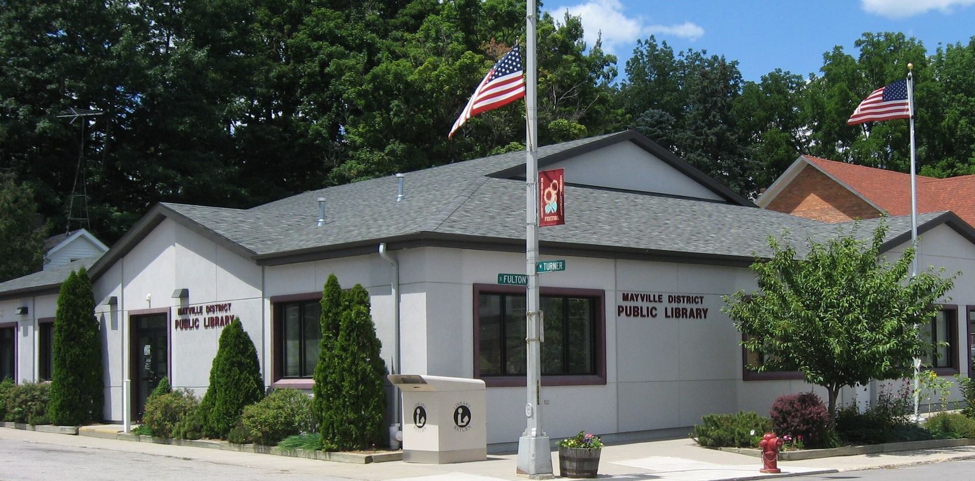 An american flag is flying in front of a white building