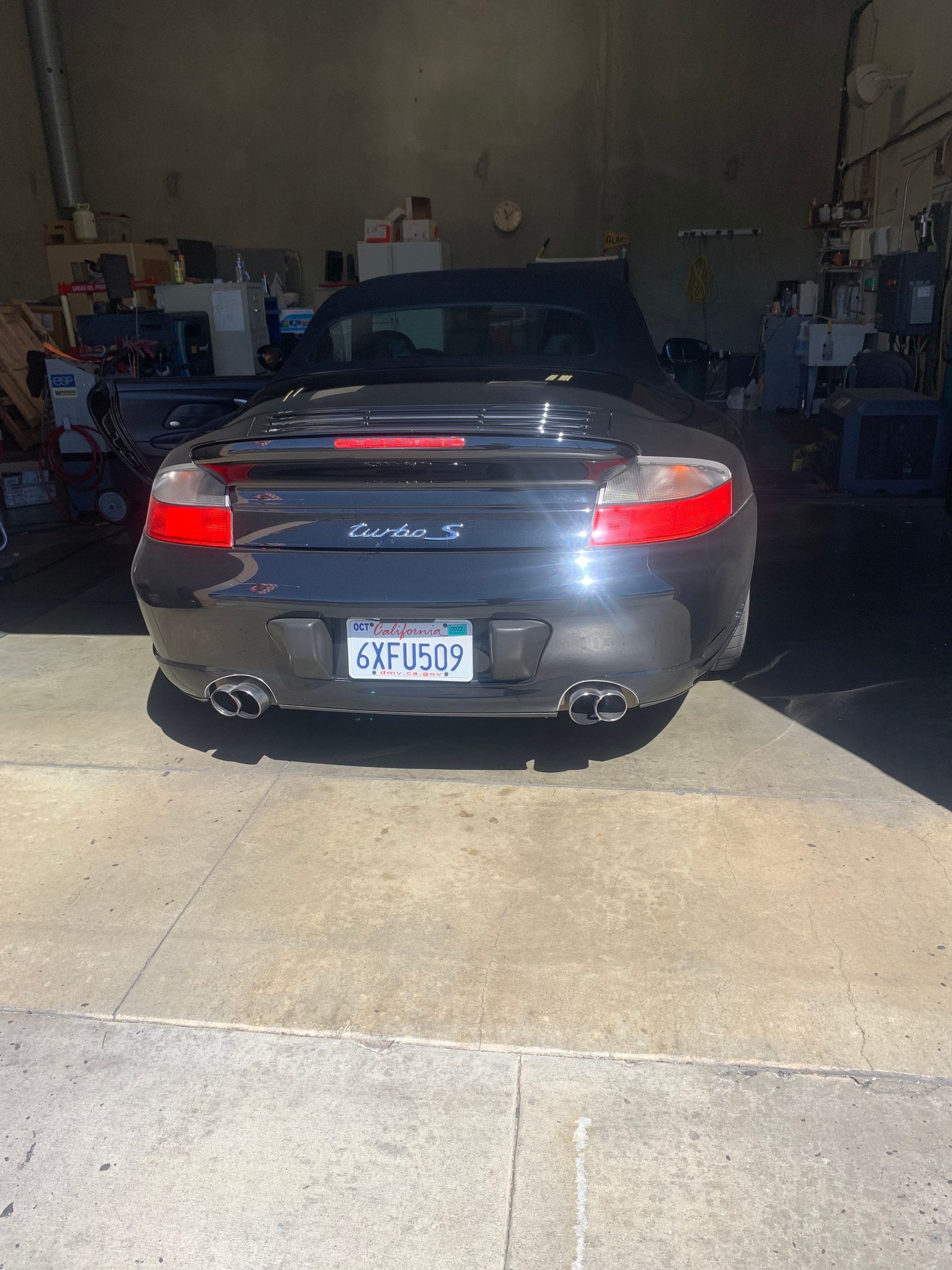 Dark grey Porsche 911 S convertible, backed into a garage, California license plate.