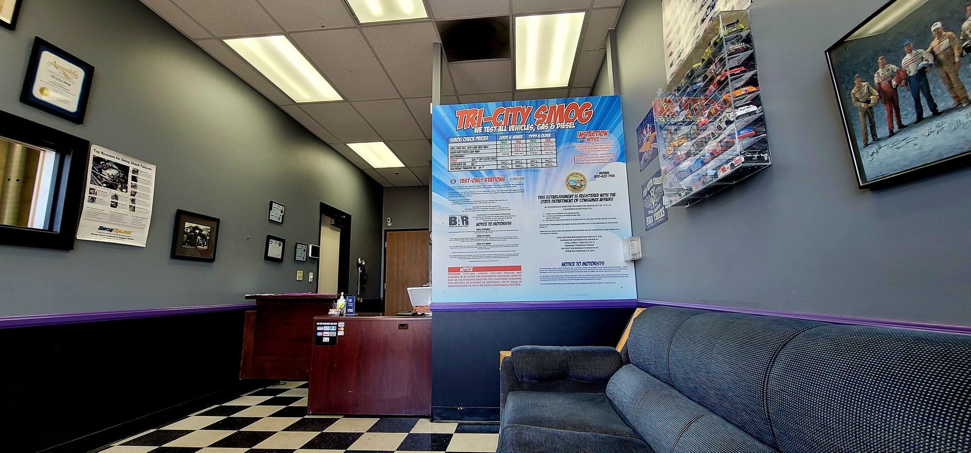 Interior of a business with black and white checkered floor, gray walls, and a black couch.