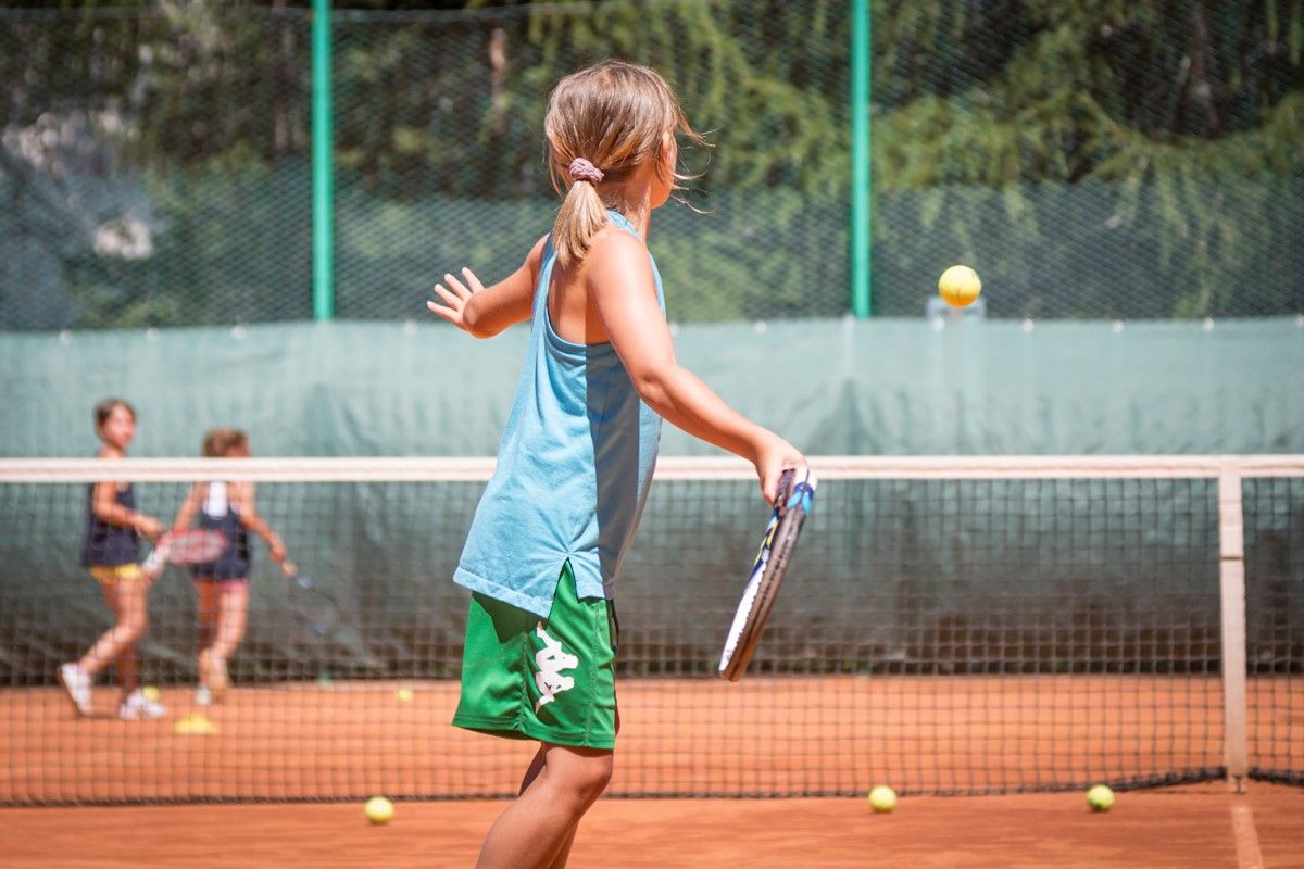 Una ragazzina sta giocando a tennis su un campo da tennis.