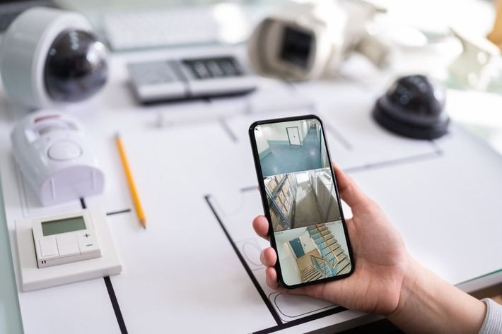 a person is holding a cell phone with a security camera on it.