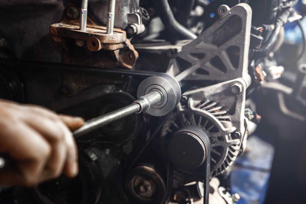 Un mécanicien serre un boulon sur le moteur d'une voiture à l'aide d'une clé.