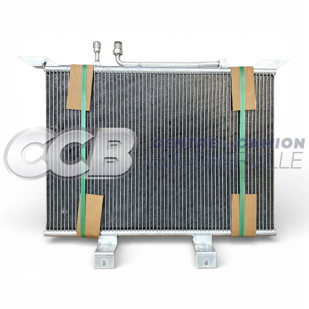 Un noyau d'évaporateur de climatisation automobile avec deux raccords de tuyauterie métalliques et des supports de montage, maintenu par des sangles vertes.