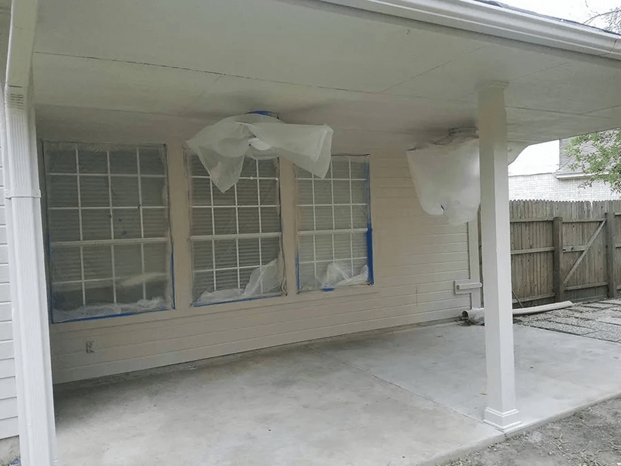 A white house with a ceiling fan and a covered patio.
