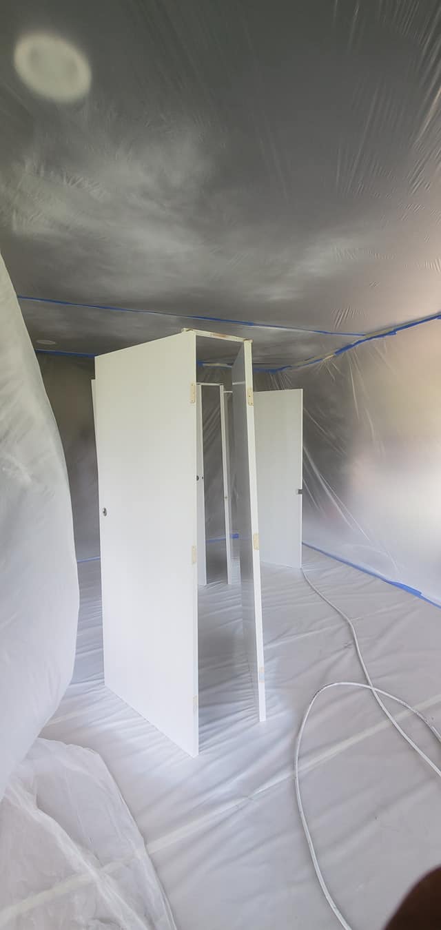 A room with white doors and a ceiling covered in plastic.