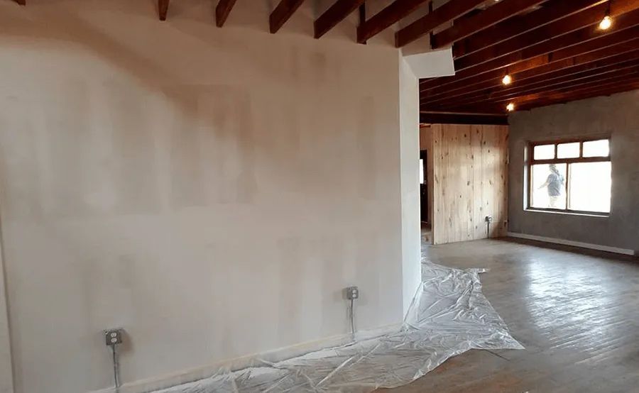 An empty room with a white wall and a wooden ceiling.