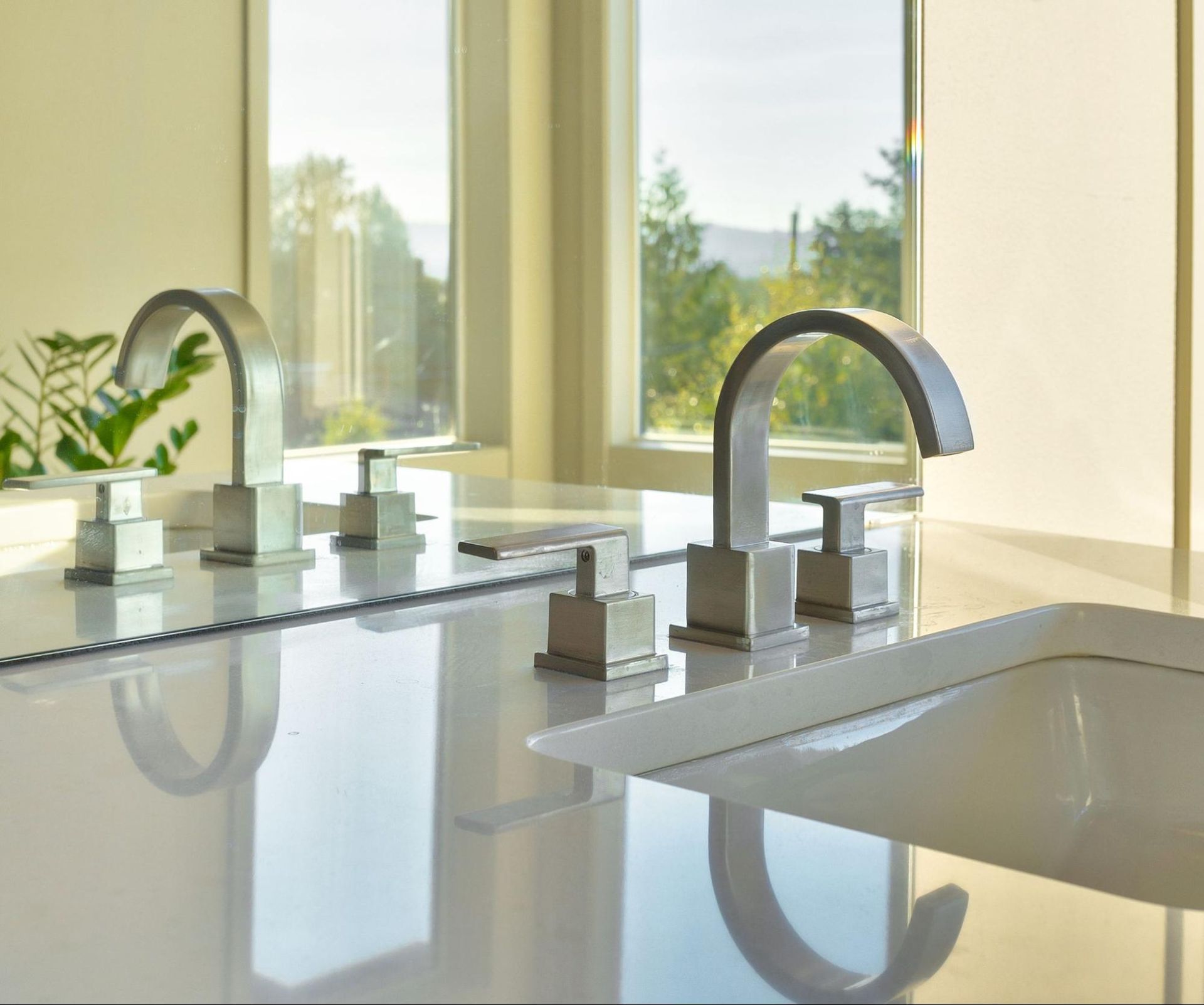 A bathroom sink with two faucets and a mirror.