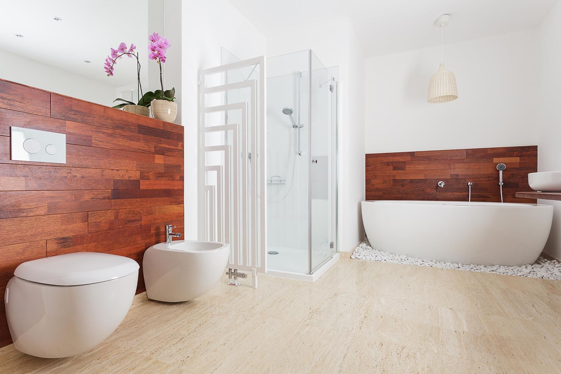 A bathroom with a bathtub , toilet , bidet and shower stall.