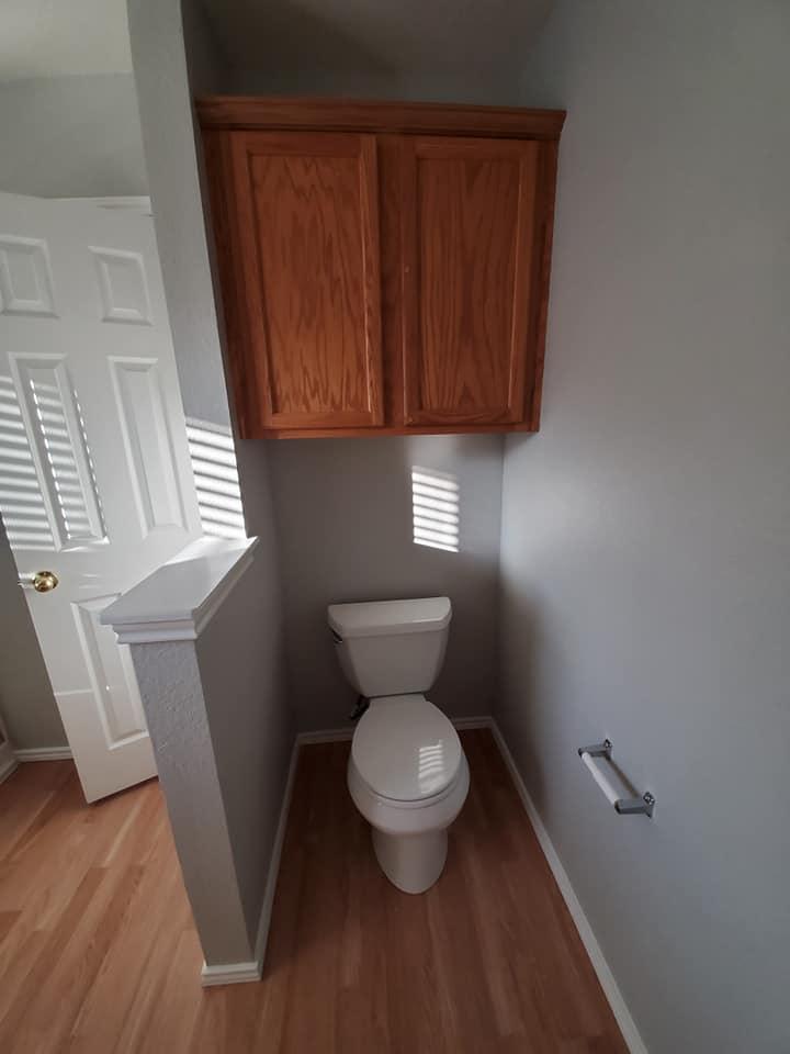 A bathroom with a toilet and a cabinet above it.