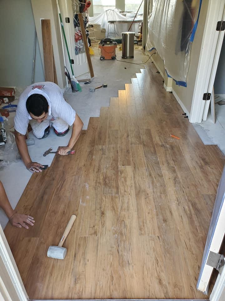 A man is installing a wooden floor in a hallway.