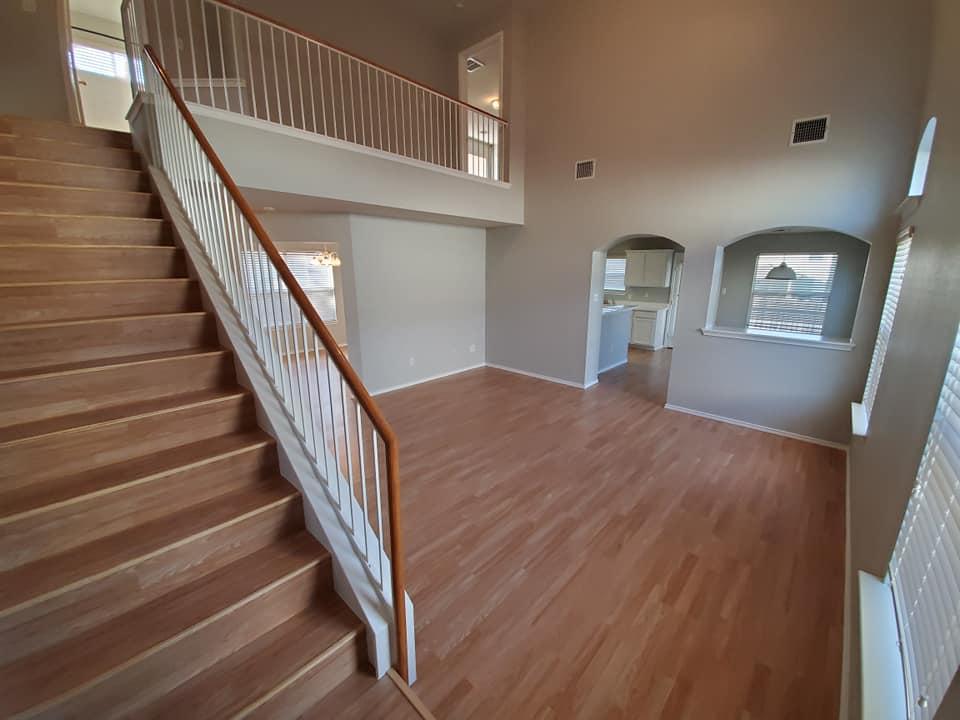 A living room with hardwood floors and stairs leading up to the second floor.