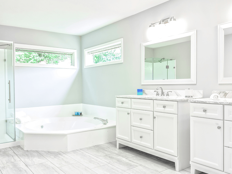 A bathroom with two sinks , a tub and a mirror.